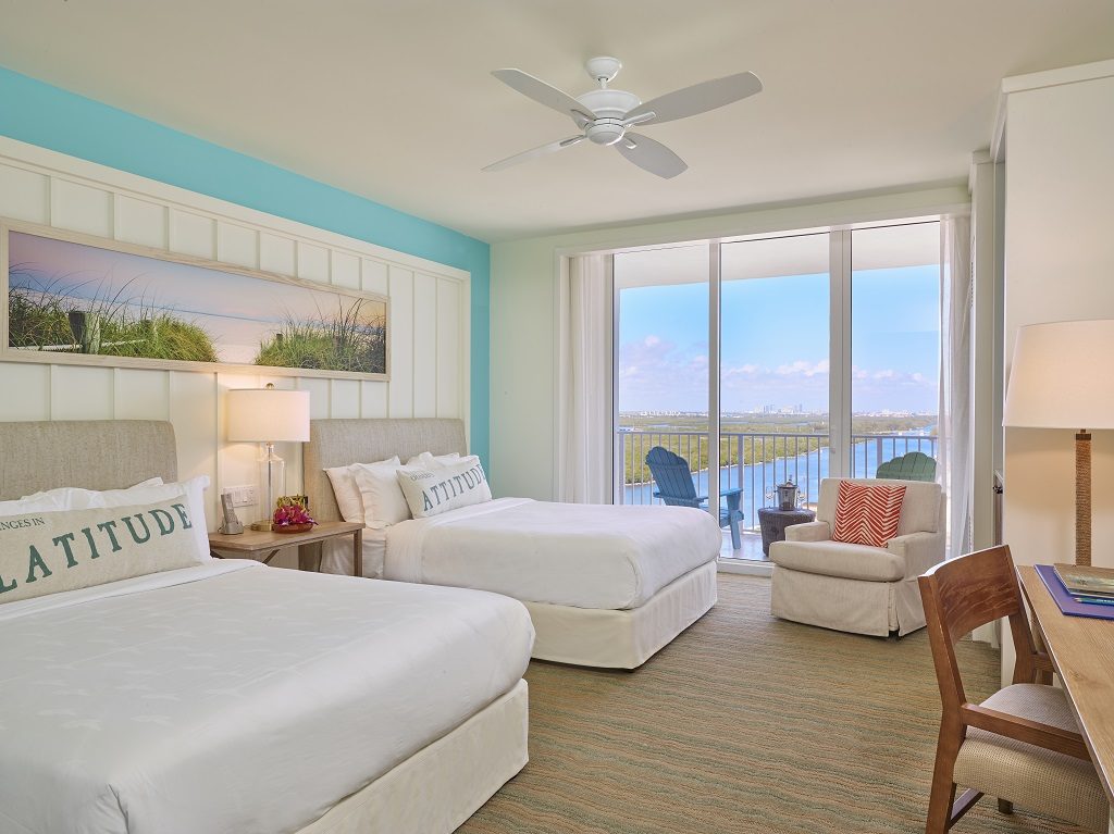 Room part with two queen beds, armchair, large window and balcony