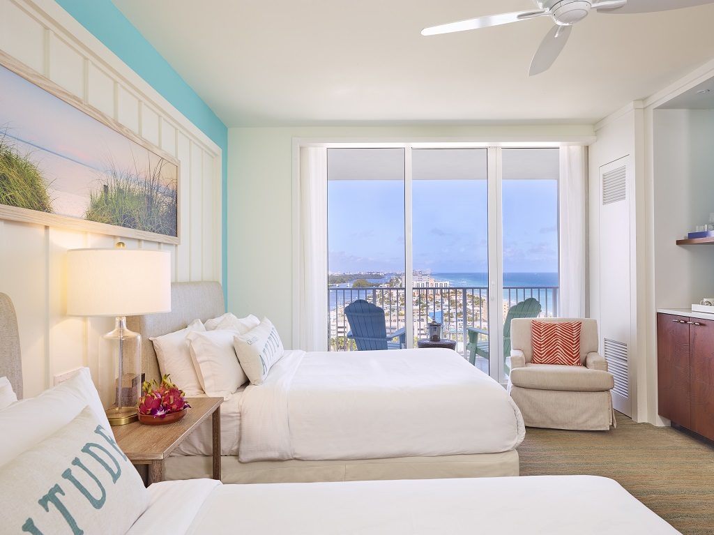 Room part with two queen beds, armchair, large window and balcony