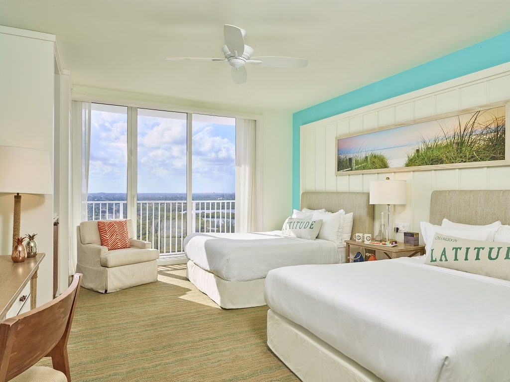 Room contemporary furnishings with a sea and sky color palette and two queen beds, armchair and large window