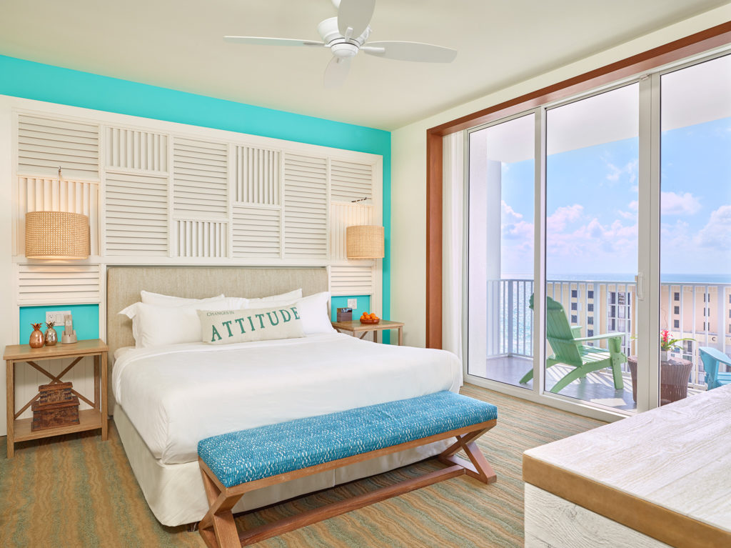Room contemporary furnishings with a sea and sky color palette, one king bed, large window and balcony