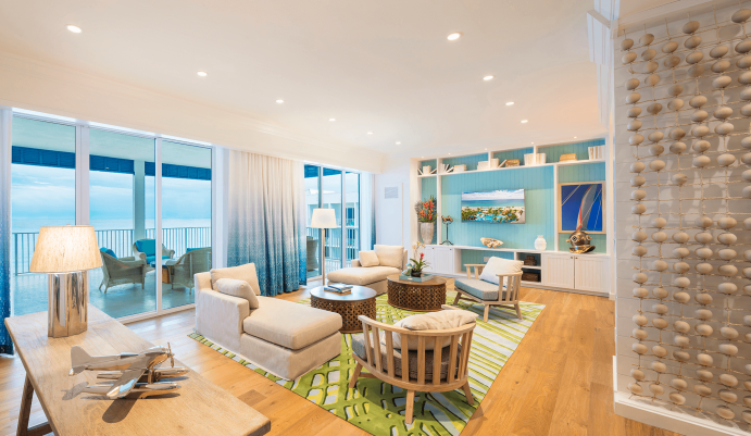Living room contemporary furnishings with a sea and sky color palette, two sofas, two armchairs, two tables and two large windows