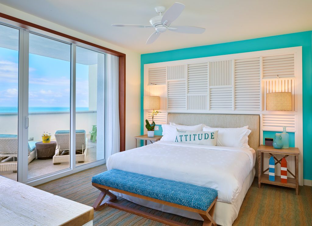 Room contemporary furnishings with a sea and sky color palette, one king bed, large window and veranda