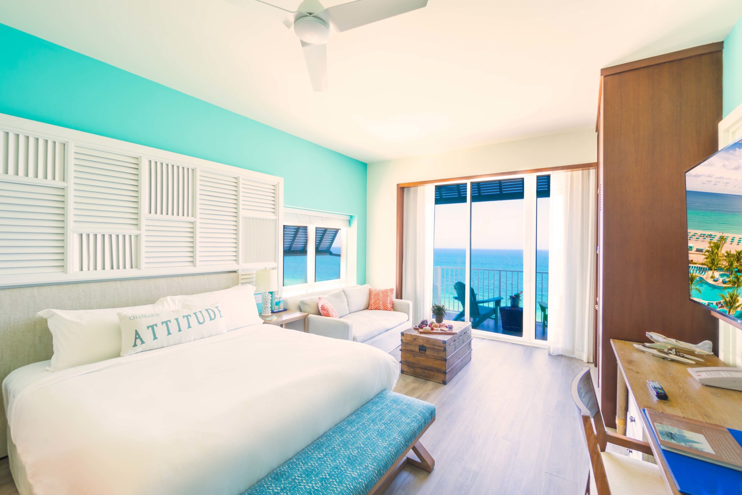 king bed and couch on left, desk on right, facing sliding balcony door with ocean view