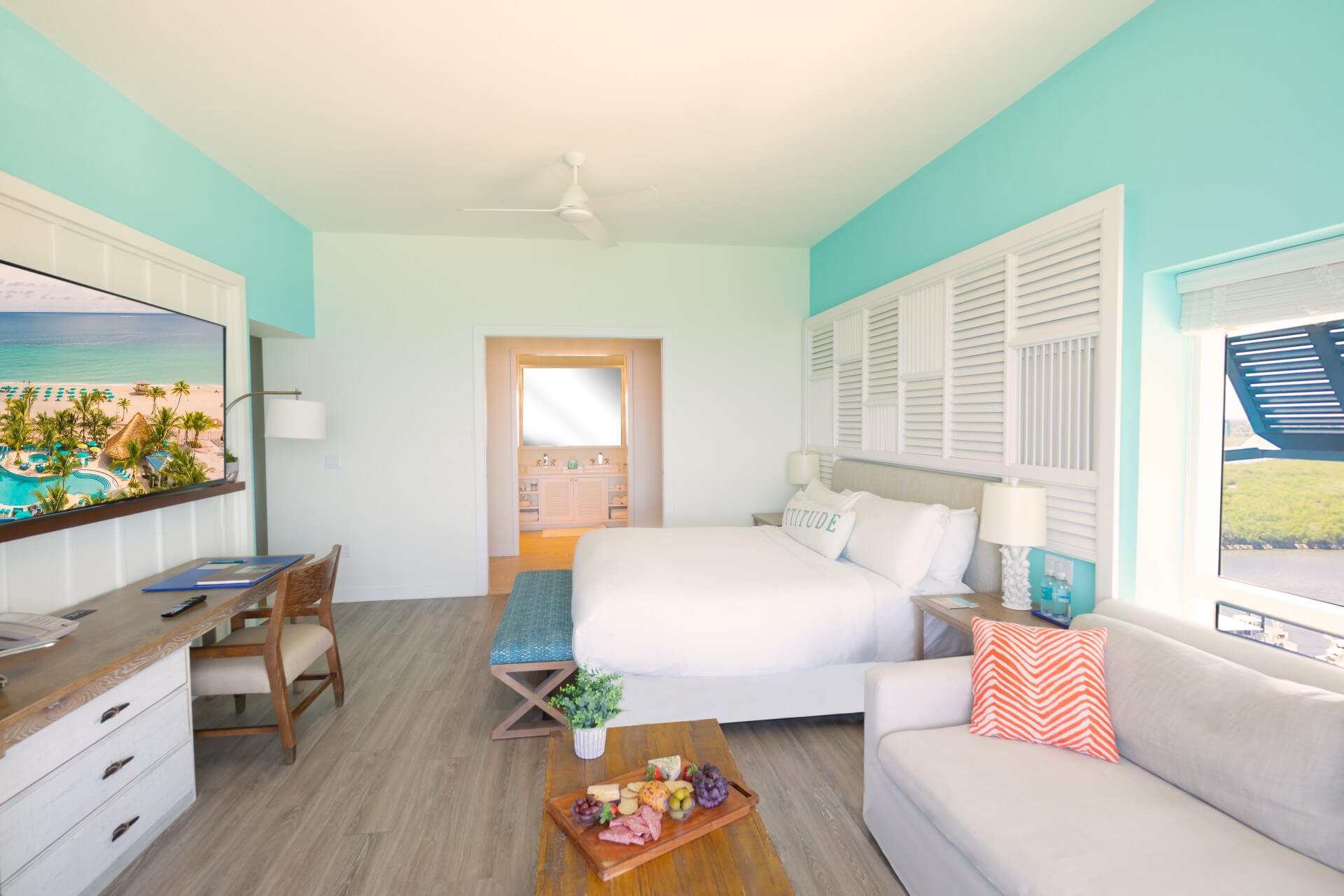 desk on left, couch and king bed on right facing in from balcony